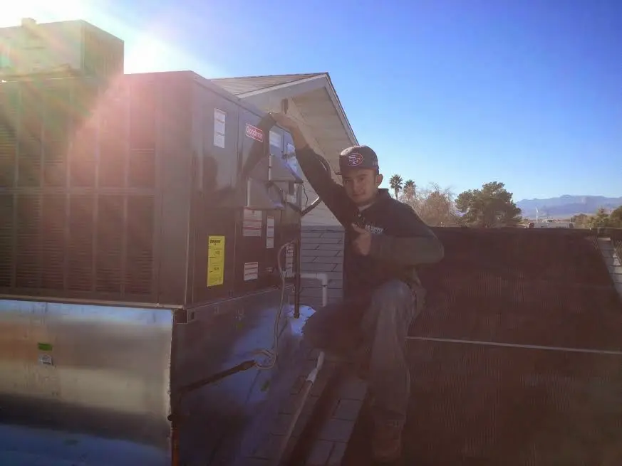 HVAC technician performing AC Tune-Up on a rooftop unit in Hitchcock